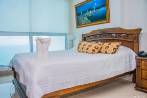 Schlafzimmer mit einem Bett mit weißer Bettwäsche und einem Fenster in der Unterkunft De Lujo-Palmetto Eliptic Playa Panoramico in Cartagena de Indias