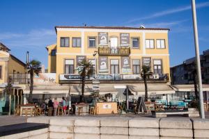a yellow building with people standing in front of it at Furabeach Alojamentos in Furadouro