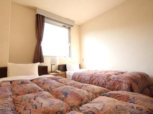 a hotel room with three beds and a window at Hotel Okuni (Royal Inn Group) in Okaya