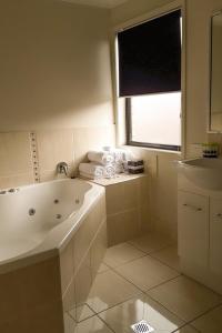 a white bathroom with a tub and a window at Atricom in Stanthorpe
