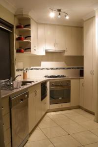 a kitchen with white cabinets and a stove top oven at Atricom in Stanthorpe