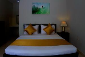 ein Schlafzimmer mit einem Bett mit gelben und weißen Kissen in der Unterkunft Ropik & Alik Home Stay in Uluwatu