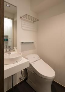 a white bathroom with a toilet and a sink at Hotel SUI Ginza Kyobashi by ABEST in Tokyo