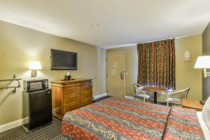 a hotel room with a bed and a flat screen tv at Wake Inn in Raleigh
