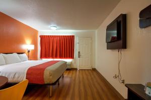 a hotel room with a bed and a television at Super 7 Inn in Tupelo