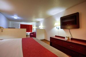 a hotel room with a bed and a flat screen tv at Super 7 Inn in Tupelo