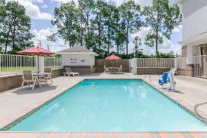 a pool with chairs and tables and umbrellas at Studio 6-Lafayette, LA - Broussard in Lafayette
