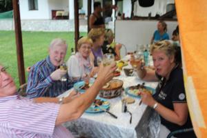un grupo de personas sentadas en una mesa comiendo comida en Casuta Didi, en Brezoi
