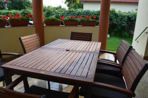 a wooden table and chairs on a porch with flowers at Pensiunea Koruna in Poenari