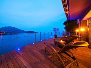 福山的住宿－米格瓦特歐馳卡慈酒店，一个带椅子和桌子的甲板,享有水景