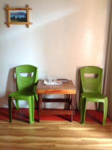 twee groene stoelen naast een houten tafel bij Holly Lodge Guest House in Shillong