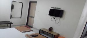 那格浦尔Anand Mahal Hotel的一间卧室，墙上有一张床和一台电视