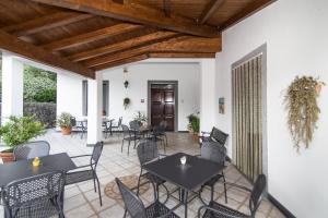 a patio with black tables and chairs and wooden ceilings at Agriturismo La Valle degli Ulivi in Trecchina