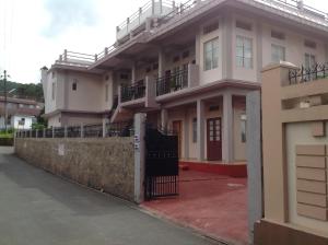 een wit huis met een hek ervoor bij Holly Lodge Guest House in Shillong