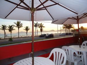 Mira Maré Praia Hotel في غوارويا: طاولة وكراسي مع مظلات وشاطئ