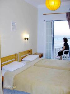 a woman sitting on a chair in a room with three beds at Atlantis Hotel in Myrties