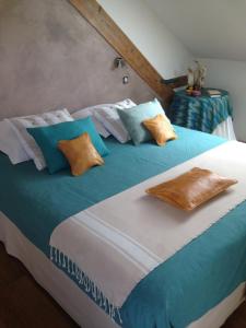 Cama grande con sábanas y almohadas azules y blancas en chambres d'hotes " Le Magnolia ", en Sainte-Croix-aux-Mines