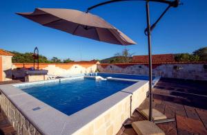 an umbrella sitting next to a swimming pool at Villa Kata in Vrpolje