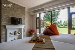 a living room with a large bed and a fireplace at DoiTung Lodge in Ban Rai