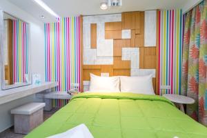 Un dormitorio con una cama verde y una pared colorida en The Elegant Apartments en Pefkari