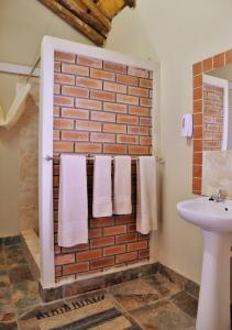 uma casa de banho com toalhas brancas penduradas numa parede de tijolos em Thebe River Safaris em Kasane