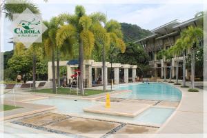 a swimming pool with palm trees in front of a building at CAROLA in Pico de Loro in Nasugbu