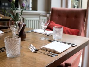 a wooden table with glasses and utensils on it at The Fleece at Cirencester in Cirencester