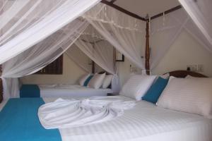 une chambre avec deux lits avec des draps blancs dans l'établissement Malee Villa (Beach Inns Holiday Resort), à Matara