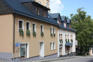 ein Gebäude mit Blumen an den Fenstern und einem Uhrturm in der Unterkunft Ferienvermietung Engelstädter in Kurort Oberwiesenthal