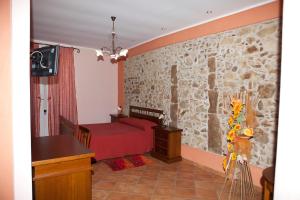a bedroom with a red bed and a stone wall at B&B Del Borgo in San Marco Argentano