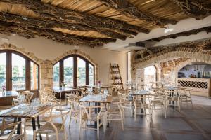 een leeg restaurant met tafels, stoelen en ramen bij Lameriana Secret Village in Lamerianá