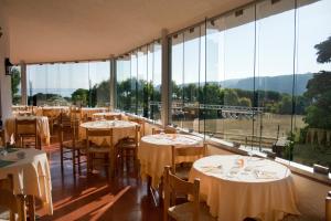 un restaurante con mesas, sillas y ventanas grandes en Hotel Mirage, en Santa Teresa Gallura