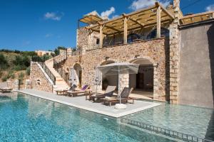 a villa with a swimming pool with two chairs and an umbrella at Lameriana Secret Village in Lamerianá