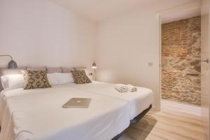 a bedroom with a white bed with a laptop on it at Flateli -Plaça Catalunya 3-2 in Girona