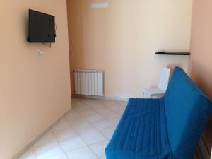 ein Wohnzimmer mit einem blauen Sofa und einem TV in der Unterkunft Casa degli Agrumi in Capo dʼOrlando