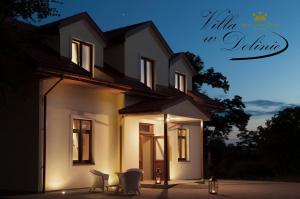 a white house with chairs in front of it at night at Apartamenty Willa w Dolinie in Tarnów