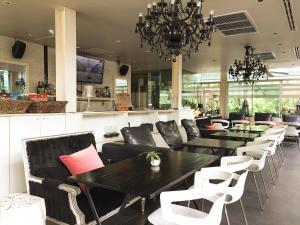 Un restaurante con mesas y sillas negras y una lámpara de araña. en Refillnow! Hostel, en Bangkok