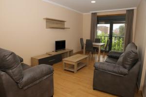a living room with couches and a television and a table at Alojamiento Caldas de Reis in Caldas de Reis