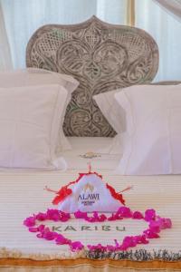 a bed with a white bed with pink flowers on it at Alawi Home in Watamu
