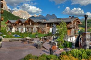 a log house with a patio in front of it at Hotel Fanes in San Cassiano