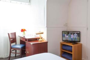a bedroom with a television and a bed at Hôtel Les Gens De Mer Lorient by Popinns in Lorient