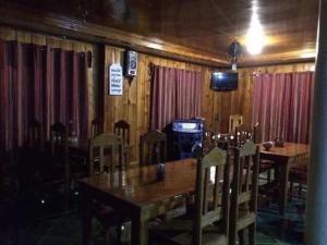 a dining room with a table and chairs and a television at Trekkers Lodge and Cafe in Banaue