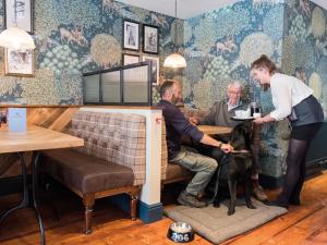 a woman petting a dog at a table in a restaurant at The Fleece at Cirencester in Cirencester