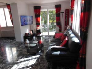 a living room with a black leather couch and windows at Un coin de campagne en ville in Le Cannet