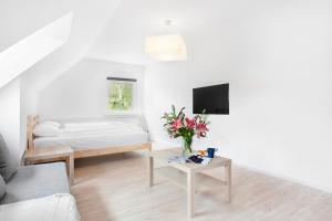 a white room with a bed and a table with flowers at Aparts Sopot in Sopot