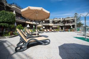 a group of chairs with an umbrella on a patio at Apartamentos Don Pedro in Playa del Ingles