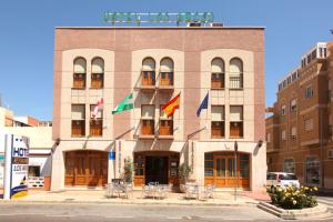 un edificio con bandiere e tavoli di fronte ad esso di Hotel Los Arcos a El Alquián