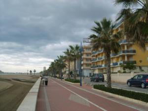 una persona caminando por una acera junto a una calle con palmeras en Apartamento con aire acondicionado en 1ª linea de playa edificio Molí de Vent, en Peñíscola