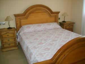 1 dormitorio con 1 cama grande de madera y 2 mesitas de noche en Apartamento con aire acondicionado en 1ª linea de playa edificio Molí de Vent, en Peñíscola