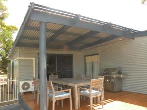 patio con tavolo e sedie in legno su una terrazza di The Anchorage Cottage Kangaroo Island ad American River